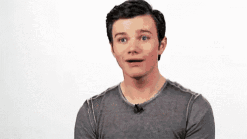 a young man is making a surprised face while wearing a gray shirt .