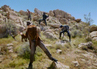 a group of people are standing on top of a rocky hillside .