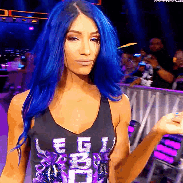 a woman with blue hair is wearing a black tank top that says legion