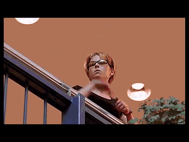 a woman wearing sunglasses stands on a staircase