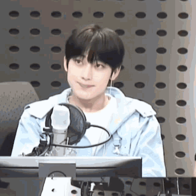 a young man is sitting in front of a microphone in front of a computer .