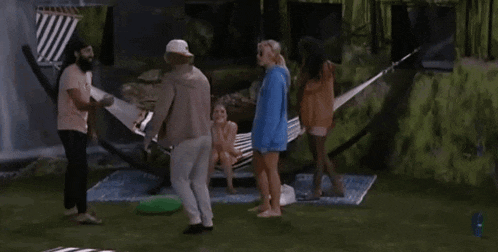 a group of people standing around a hammock with a woman sitting in it