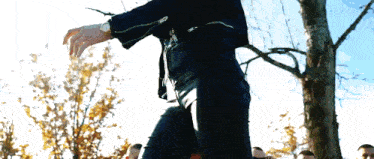 a man in a black jacket is standing in front of a group of people .