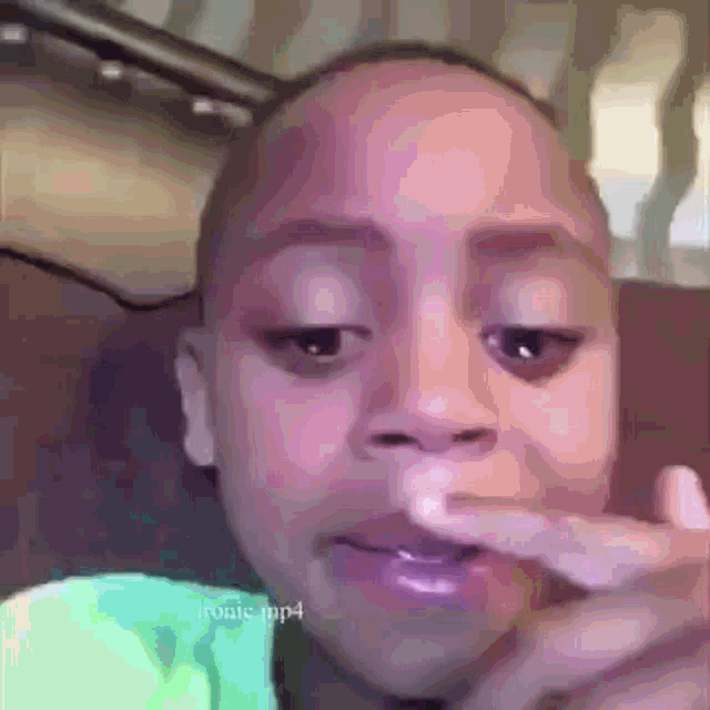 a young boy is sitting on a couch with his finger in his mouth .