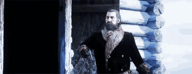 a man with a beard and a fur coat is standing in front of a log cabin