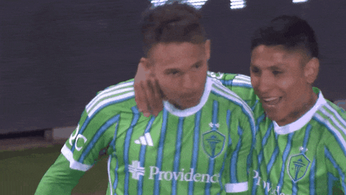 two soccer players wearing green striped jerseys with the word provident on the front