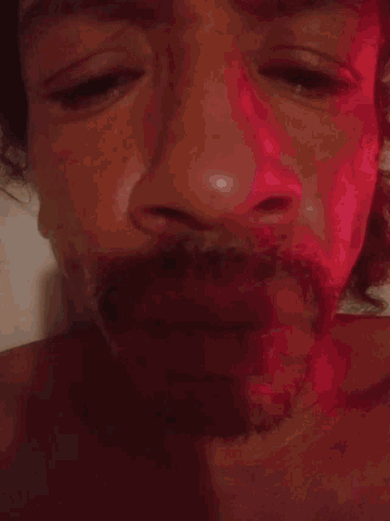 a man laying on a bed with a red light shining on his face
