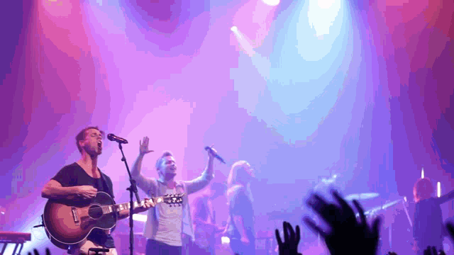 a man singing into a microphone while playing a guitar and a woman singing into another microphone