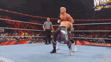 two wrestlers in a wrestling ring with a referee and a sign that says ' wrestlers ' on it