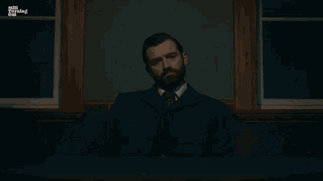 a man with a beard is sitting in front of a blackboard with the words brooding intensifies written on it