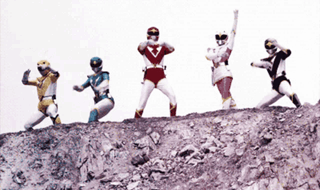 a group of power rangers are standing on a rocky hill