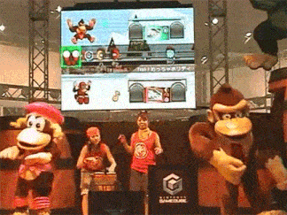 a group of monkeys are dancing in front of a large screen that says nintendo gamecube