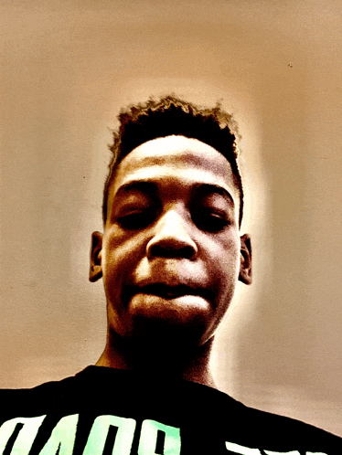 a young man wearing a black shirt that says ' and ' on it looks at the camera with his eyes closed