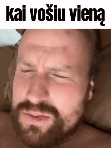 a man with a beard is laying on a bed with his eyes closed and the words kai vosiu vieną written above him