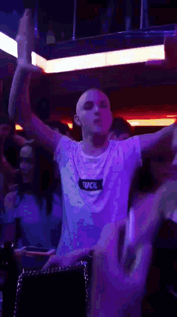 a man wearing a white shirt that says fuck is dancing in a club