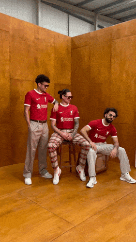 three men wearing red shirts that say ' liverpool ' on it