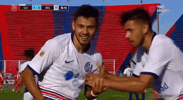 two soccer players are congratulating each other on a soccer field