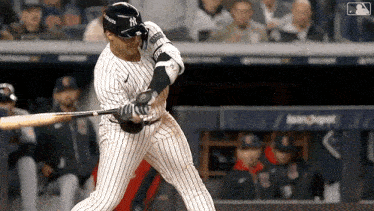 a new york yankees baseball player swings his bat at the ball