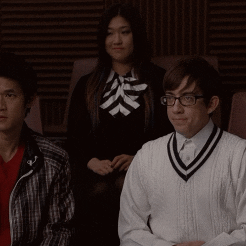 a man wearing glasses sits next to a woman