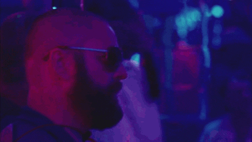 a man with a beard wears sunglasses and says ale