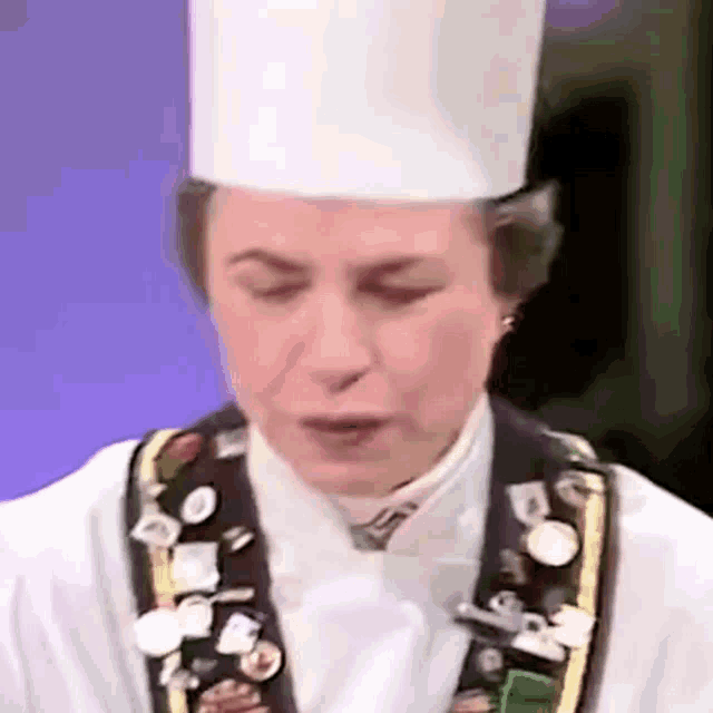a close up of a chef wearing a white hat and badges