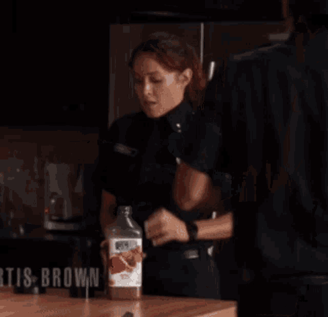 a woman in a police uniform is standing in front of a refrigerator with the name " tis brown " on the bottom