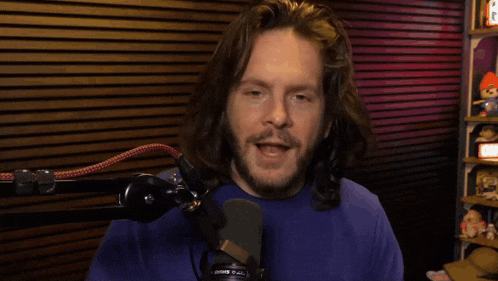 a man with long hair and a beard stands in front of a microphone with the word shure on it