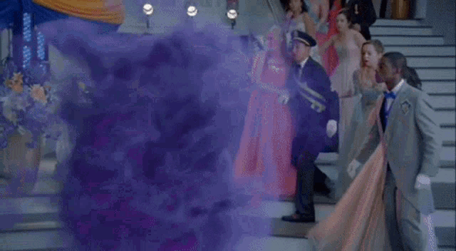 a woman with purple hair and a tiara on her head is standing in a crowd of people .