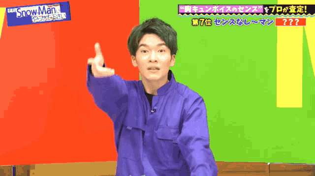 a man in a blue jacket is pointing at something in front of a sign that says snowman