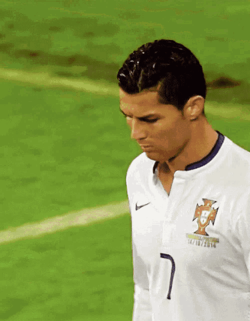 a soccer player with the number 7 on his shirt stands on the field