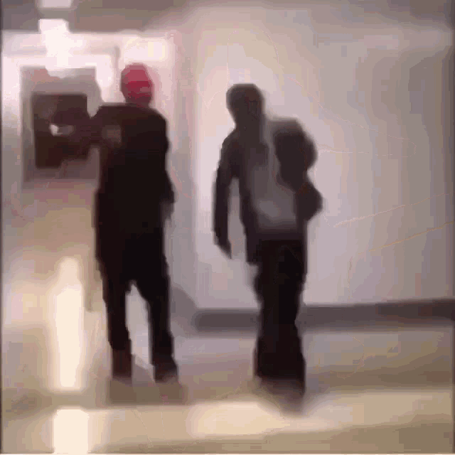 a blurry picture of two people walking in a hallway .