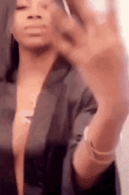 a woman in a black jacket is making a funny face with her hands .