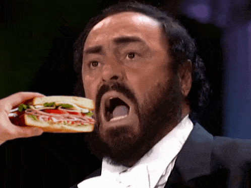 a man with a beard is eating a sandwich with tomatoes and onions