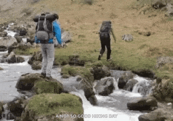 a man with a backpack is walking across a river .
