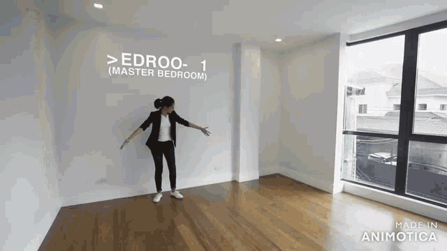 a woman is standing in a room with a sign on the wall that says edroo- 1 ( master bedroom ) .