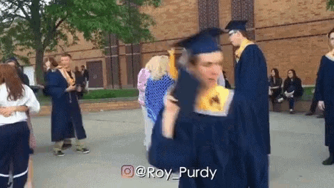 a man in a graduation cap and gown is holding a diploma in front of a crowd