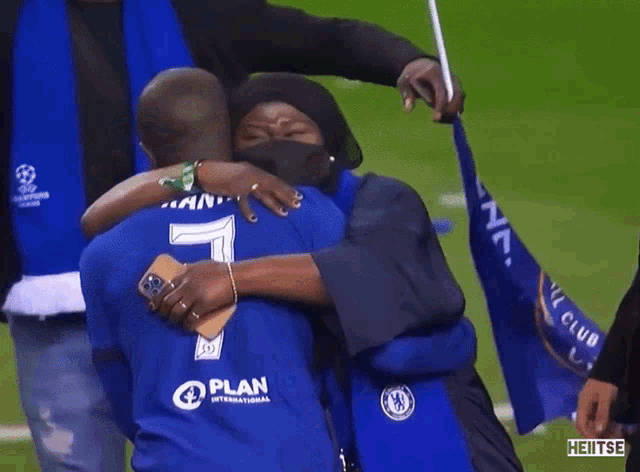 a man wearing a blue shirt with the number 7 on it is hugging another man