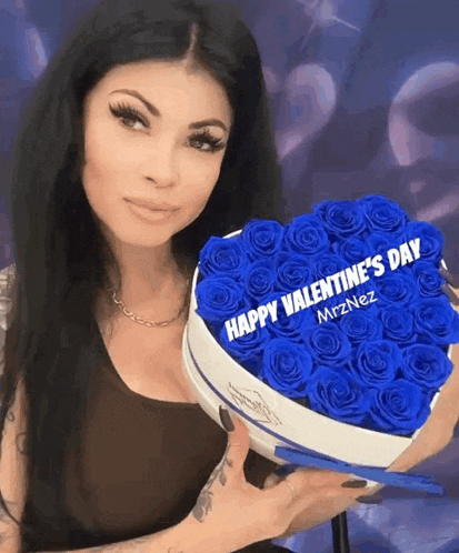 a woman is holding a heart shaped box of blue roses with the words happy valentine 's day written on it