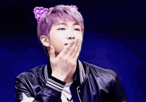 a young man with purple hair and cat ears is covering his mouth with his hand .