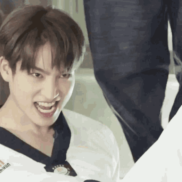 a young man wearing a taekwondo uniform is smiling with his mouth open