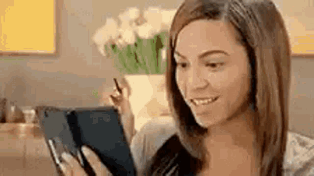 a woman is sitting on a couch looking at a tablet computer .