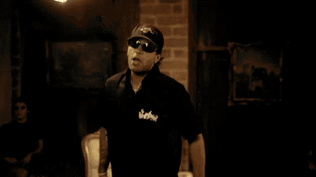 a man wearing a hat with a skull and crossbones on it stands in a dark room
