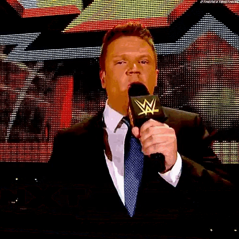 a man in a suit and tie is talking into a microphone .