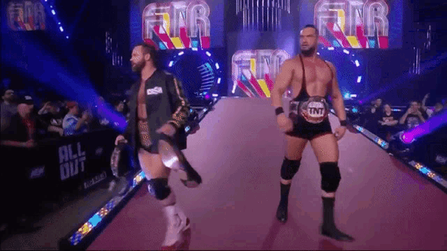 two wrestlers are walking down a red carpet with the word tnt on it