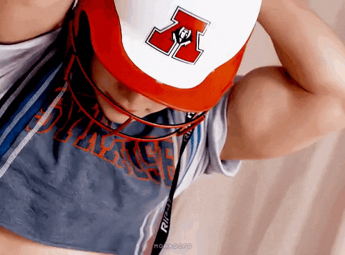 a man wearing a baseball cap and a crop top is looking down .