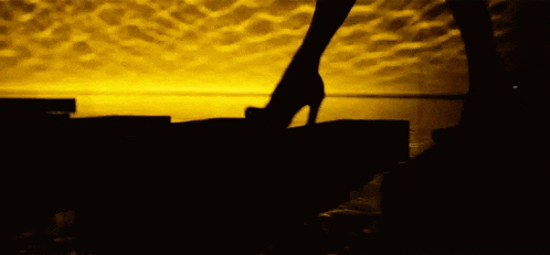 a silhouette of a person standing in the dark with a yellow background .