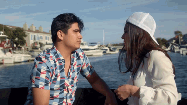 a man and a woman are looking at each other while sitting on a boat