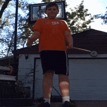 a boy wearing an orange shirt with the number 35 on it stands in front of a basketball hoop