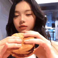 a woman is holding a hamburger in her hands and eating it