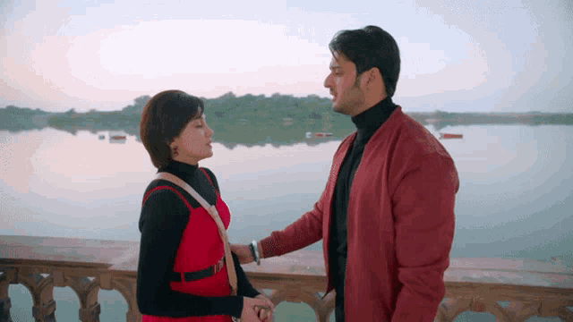 a man in a red jacket is holding a woman 's hand